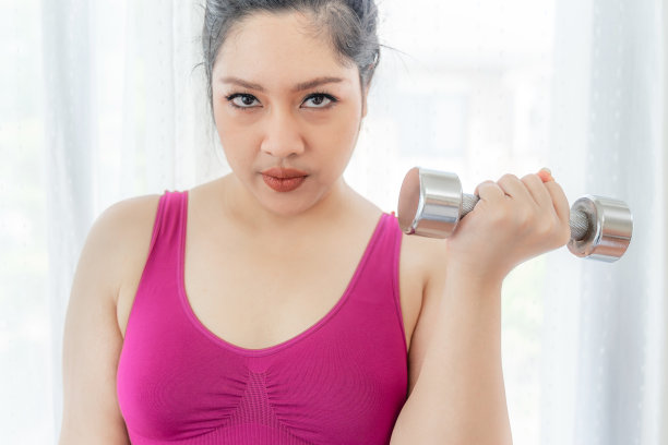 亚洲胖女人，胖女孩，胖嘟嘟的，超重加尺寸的尝试练习在卧室举哑铃-生活方式女性减肥超重问题的概念图片下载