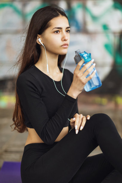 穿着黑色运动服的年轻女子在训练后听音乐和休息图片下载