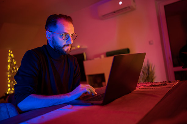 穿着西装的严肃英俊的白人商人倚在桌子上看图表。深夜工作的概念。库存图片图片下载