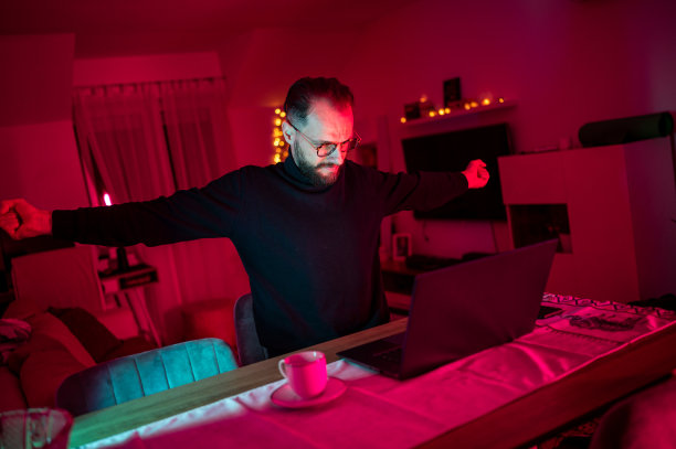 穿着西装的严肃英俊的白人商人倚在桌子上看图表。深夜工作的概念。库存图片图片下载