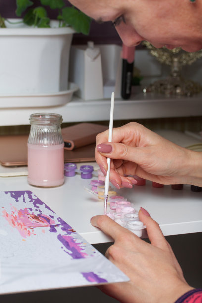 这个女人用数字作画。画布上的丙烯颜料。附近是油漆罐和其他配件。图片下载