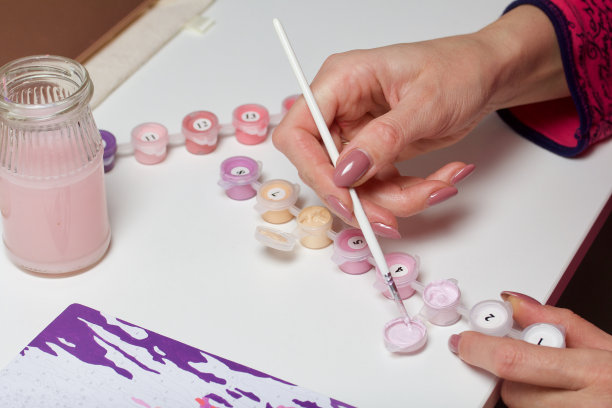 这个女人用数字作画。画布上的丙烯颜料。附近是油漆罐和其他配件。图片下载