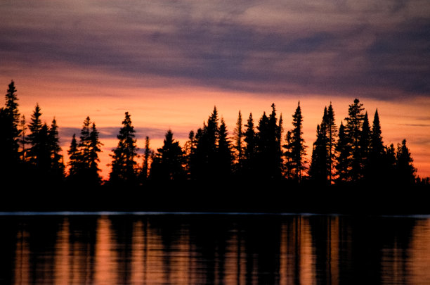美丽的彩色照片多云的日落在水上与树木在背景的股票摄影图片下载