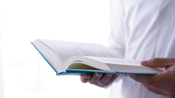 一个人站在窗边，手里拿着书在读图片下载