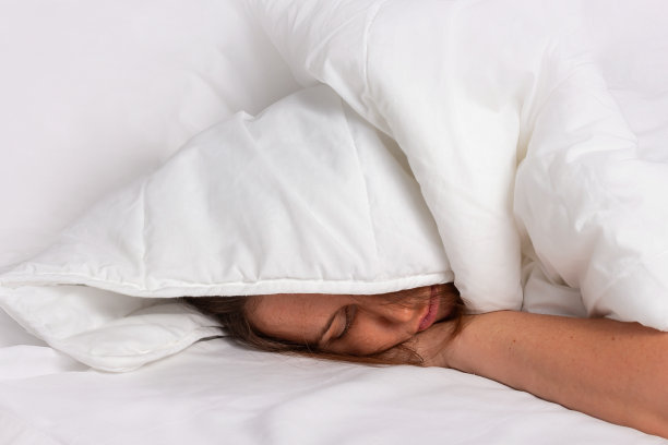失眠的概念。睡在白色毯子下的女人。图片下载