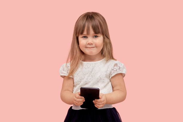 一个漂亮可爱的女孩手里拿着手机的肖像。看着摄像机图片下载