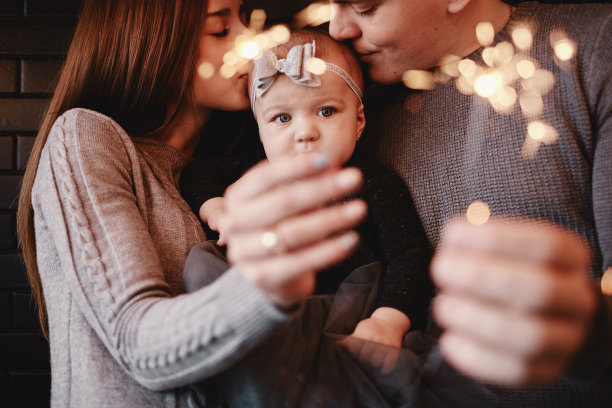 幸福家庭的肖像，妈妈，爸爸和宝贝女儿与火花和光。一家人期待圣诞节的到来。选择性的照片。图片下载