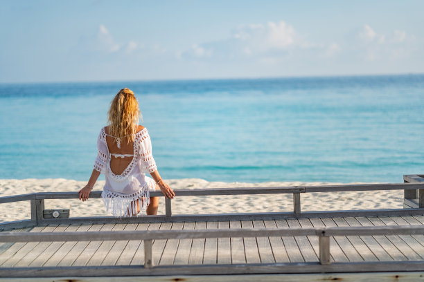 女人正坐在木制的防波堤上欣赏风景图片下载