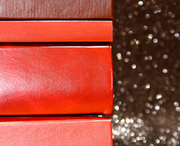 以黑色为背景的一堆书许多五颜六色的书。书排成一长排。图片下载