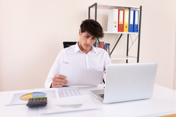 紧张的商人看着图形并在电脑上做笔记图片下载