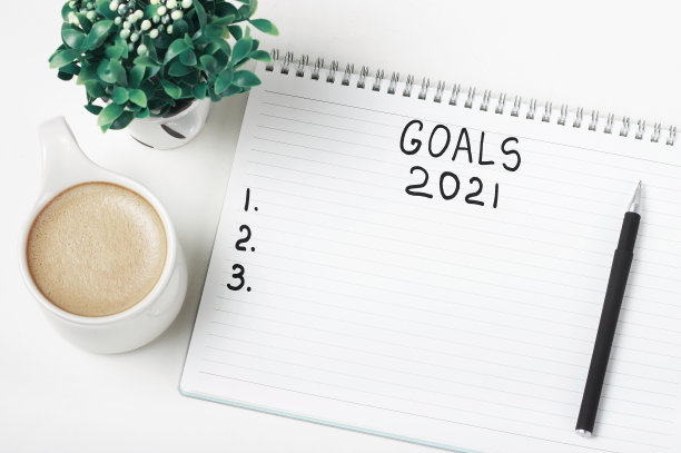 记事本上的目标2021年和一杯咖啡在白色的背景。图片下载