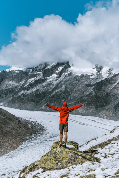 徒步旅行者在瑞士阿尔卑斯山的冰川上放松，张开双臂图片下载