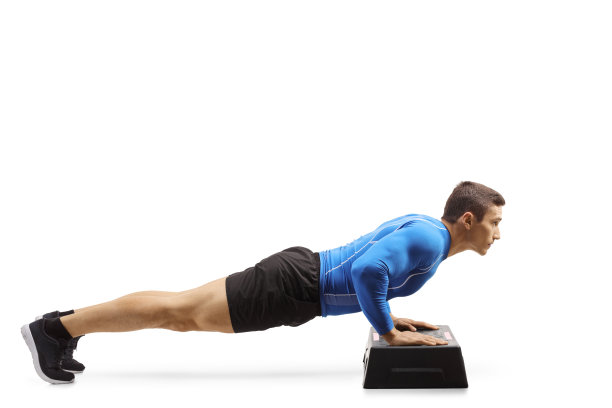 强壮的年轻人在一个踏步有氧平台上做俯卧撑图片下载