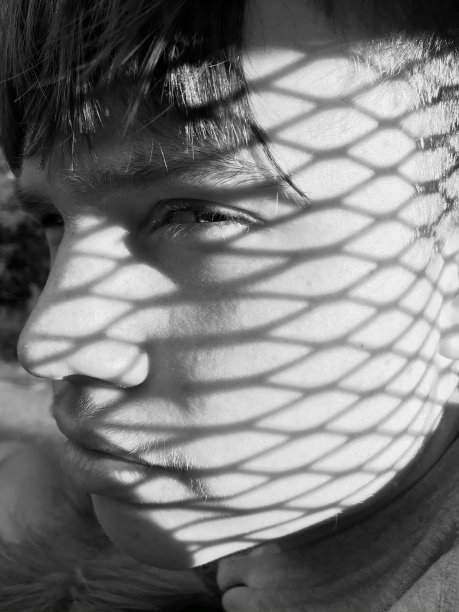 一个表情严肃的少年的肖像，脸上的阴影。图片下载