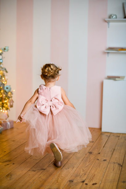 全长小女孩的后视图在美丽的粉红色连衣裙与领结图片下载