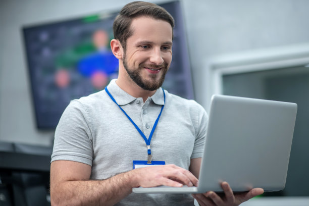 快乐的男人站在办公室里用笔记本电脑工作图片下载