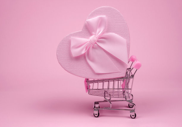 粉色心形礼物与蝴蝶结为情人节购物货架上粉红色的背景，快递礼物图片下载