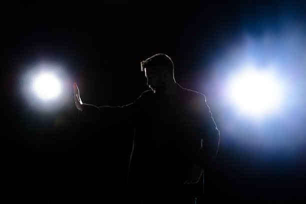 在灯笼的灯光下，孤独的人影在黑暗的背景上保护着自己图片下载