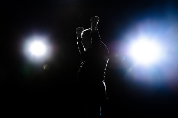 裹着面包的人的剪影，双手举在黑暗的背景上。图片下载