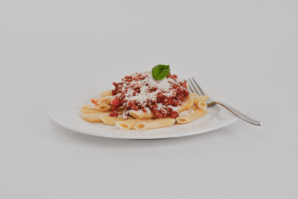 近距离的一盘煮熟的意大利面与磨碎的奶酪，肉酱和一个叉子图片下载