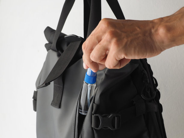 保护冠状病毒的概念:消毒酒精喷雾剂(洗手液或杀菌剂)的瓶子男子拿下来放在背包里。图片下载