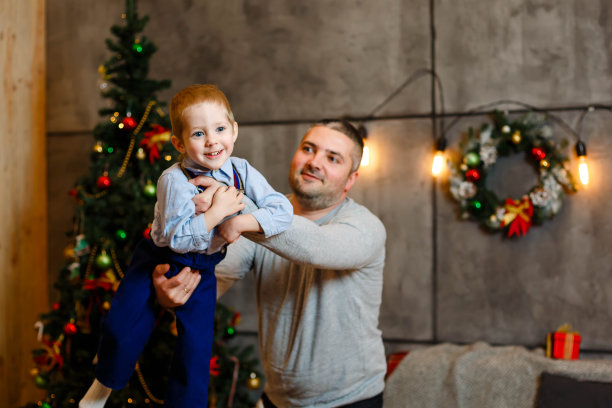 快乐的小爸爸在家里抱着兴奋快乐的小儿子图片下载