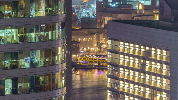 玻璃钢结构多层建筑的窗户，内部灯光明亮，人影穿梭图片下载