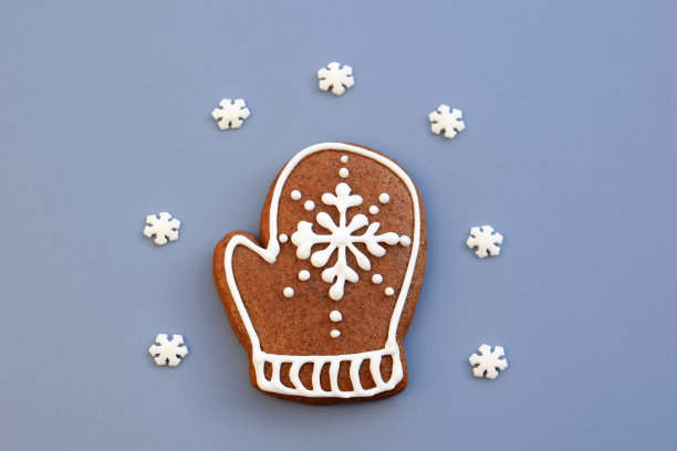 姜饼手套装饰白色糖霜和小糖雪花在浅蓝色的背景图片下载