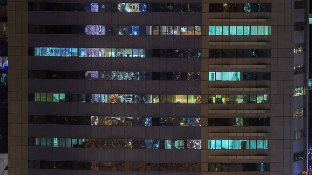 玻璃钢结构多层建筑的窗户，内部灯光明亮，人影穿梭图片下载