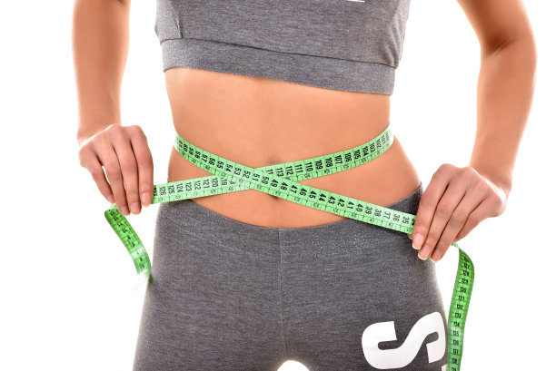 女人测量她的完美腰部在白色的背景图片下载