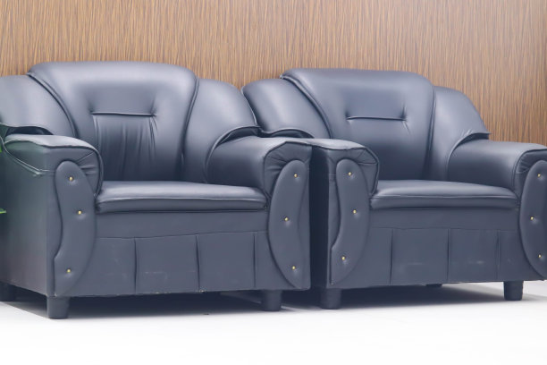 现代装饰豪华的黑色真皮沙发，白色瓷砖地板和木质纹理墙的家庭室内设计概念或酒店办公室客人等候休息室图片下载