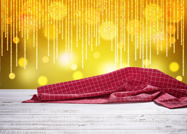 木制书桌与红色桌布和黄色闪烁的灯光背景散焦。图片下载