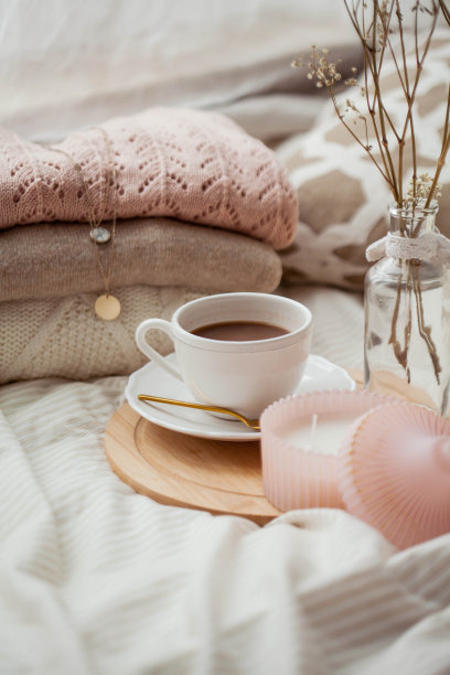 一杯热可可，针织毛衣，花瓶里放着一束白色干花，床上放着一支蜡烛。早餐在床上。舒适。图片下载