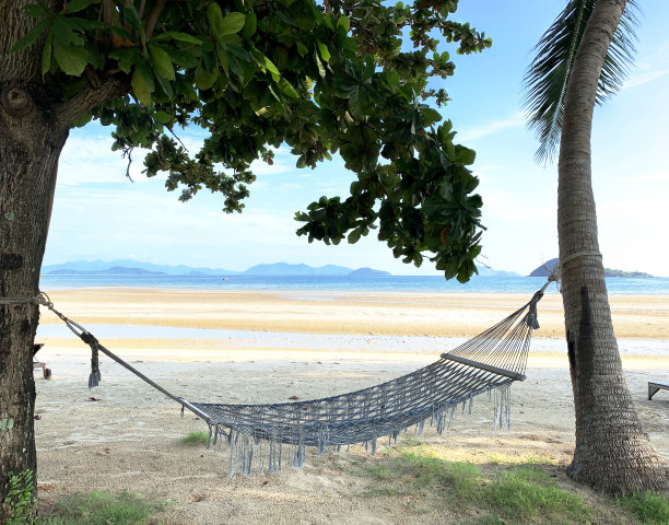 一个美丽宁静的下午，放松的海边气氛。在树荫下的布质吊床和木制的泳池床，风舒适地吹着，高窑诺伊，特拉特，泰国。图片下载