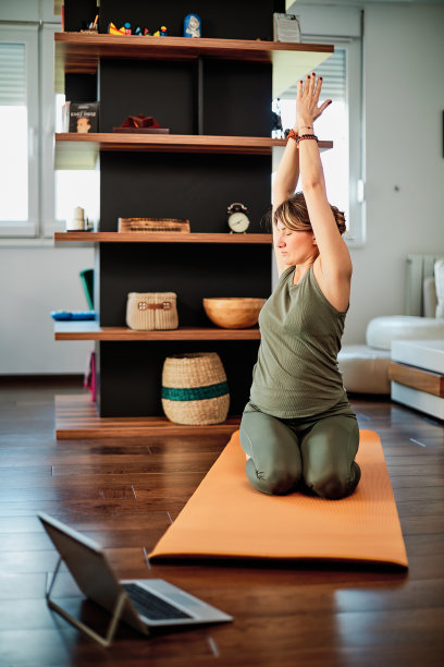 女人在家里练习瑜伽视频教程。图片下载