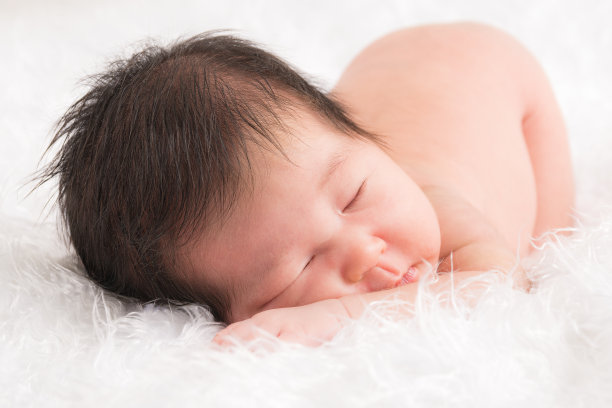 可爱的新生婴儿躺在白色的毯子里。素材图片