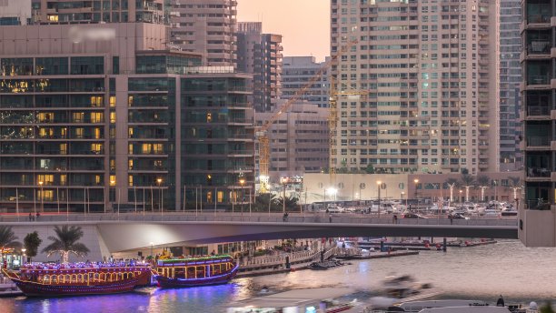 迪拜码头区，购物中心附近的游艇和船只，桥下游客穿梭（延时摄影）图片下载