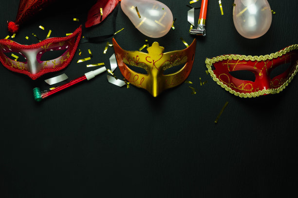 桌面鸟瞰图美丽多彩的狂欢节节日背景。平铺配件对象的几个面具和装饰五彩纸屑在现代黑色木制的家庭办公室办公桌工作室。副本的空间。图片下载