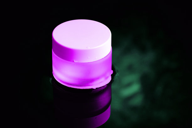 水里放着一个白色盖子的粉色玻璃罐子。黑暗的主题。图片下载