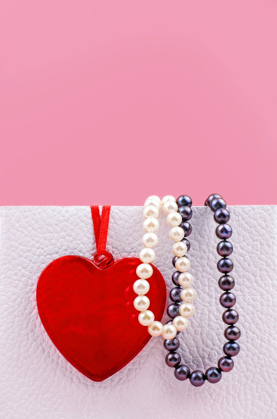 红色的心和珍珠珠，白色的包装，粉红色的背景，特写。垂直的照片。本空间图片下载