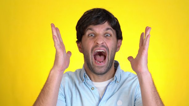 近距离的震惊的男人的脸。在黄色的背景下，一个英俊的男人惊讶地看着镜头图片下载