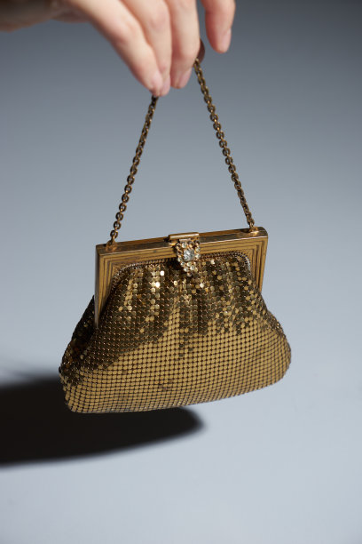 女人手里拿着金色的钱包。蓝色背景的女手提包图片下载