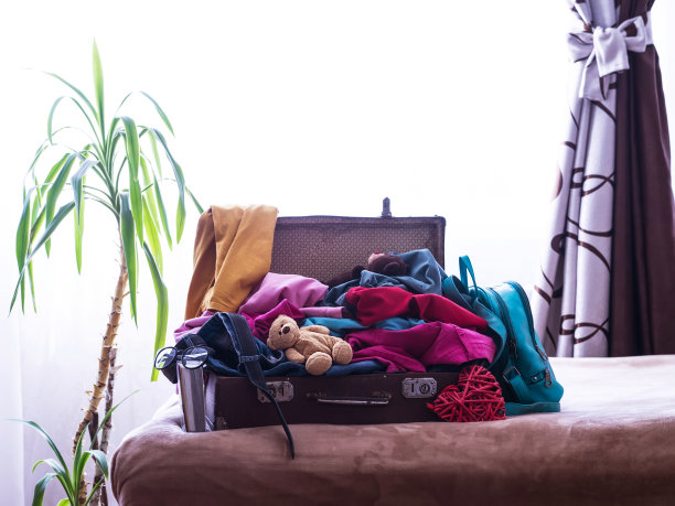 一个装满衣服的旧旅行箱。旅行的概念。复古的手提箱，装满了度假的东西，叠得漫不经心的衣服。旅行的概念。旅行。图片下载
