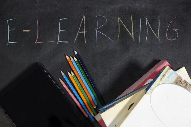 书和黑板上的写字板。电子学习的学校。图片下载