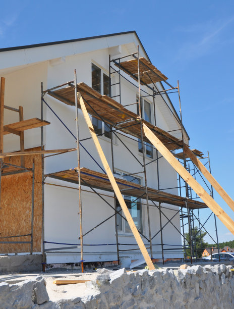 房屋翻新外立面用墙体保温、抹灰、粉刷墙壁。房屋改造建筑外立面有脚手架。图片下载