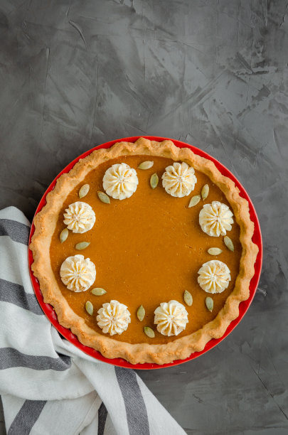 传统的节日南瓜派，黑色的石头背景上撒有香料、鲜奶油和种子。感恩节的甜点。图片下载