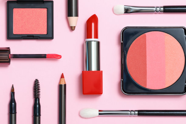 粉红色背景上的装饰性化妆品。化妆刷，腮红和口红。平躺，俯视图。图片下载