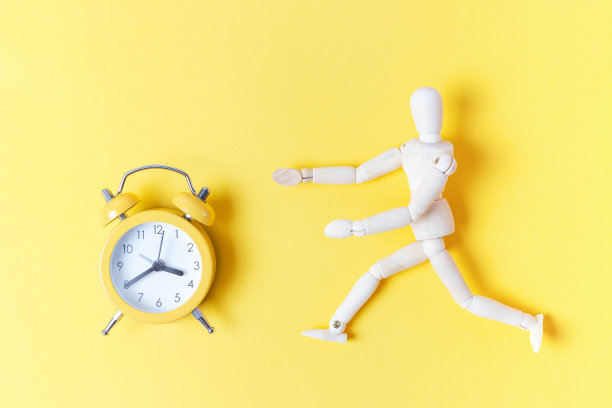木头人跑到黄色背景的闹钟，期限概念图片下载