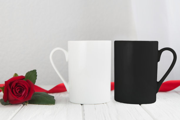 情人节杯子，白色和黑色的杯子放在木桌上，白色的背景是红玫瑰图片下载