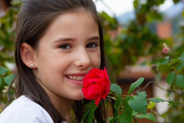 微笑的小女孩闻着红玫瑰图片下载